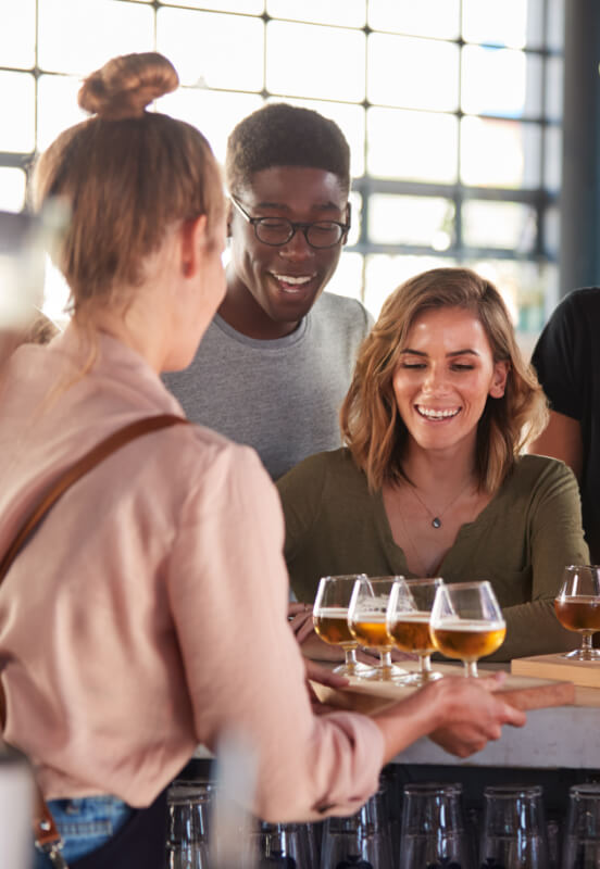 a couple of young adults at a bar taste testing beers